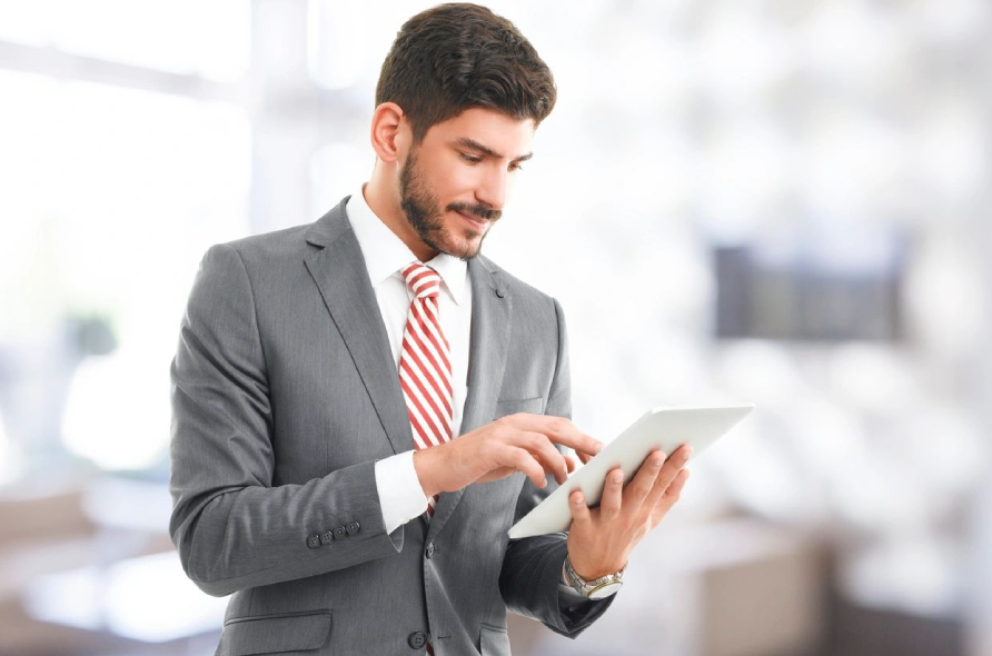 A man in a suit and tie holding a tablet.